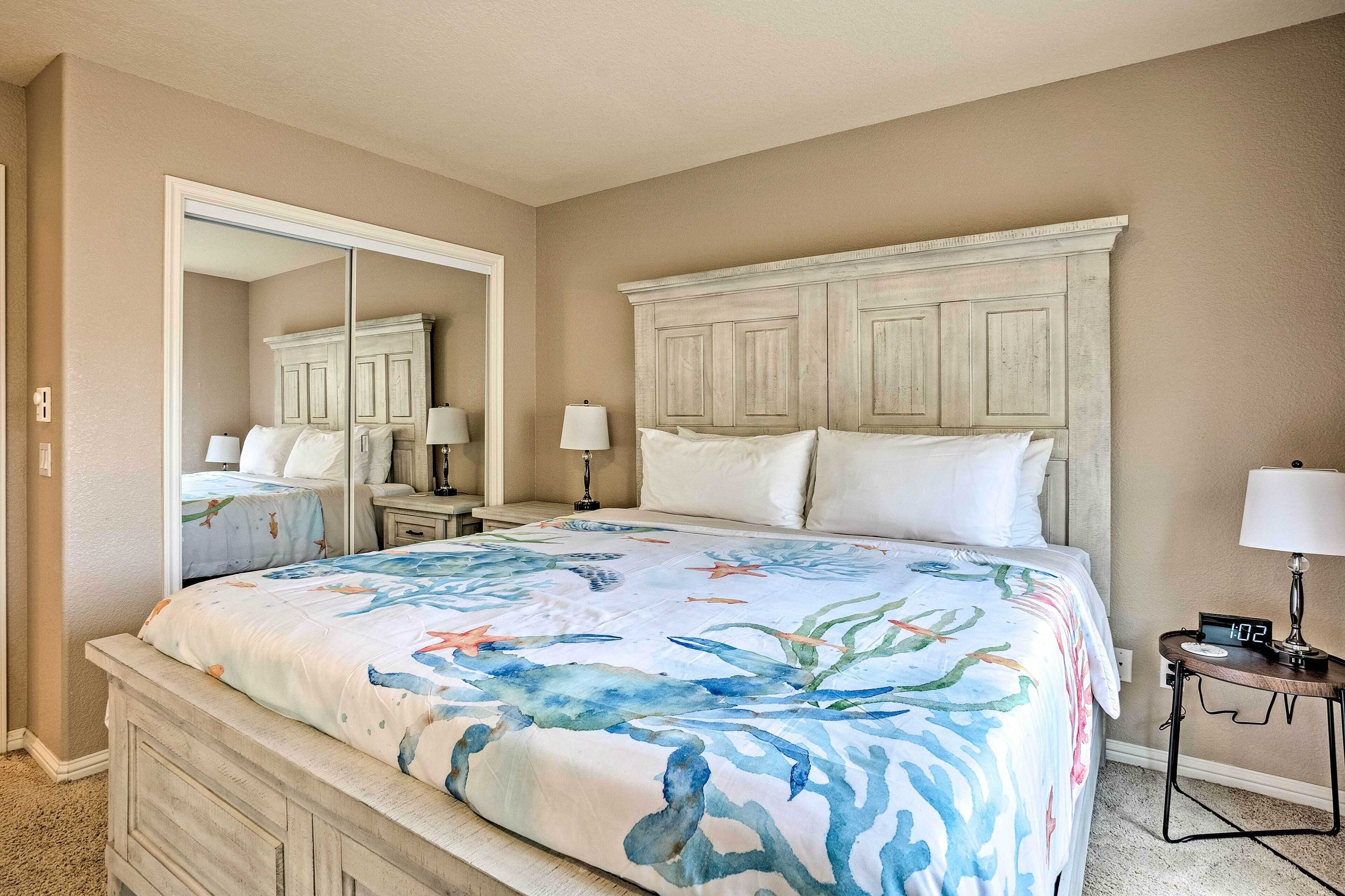 A bedroom with a bed, nightstands, a mirror, and a digital clock.