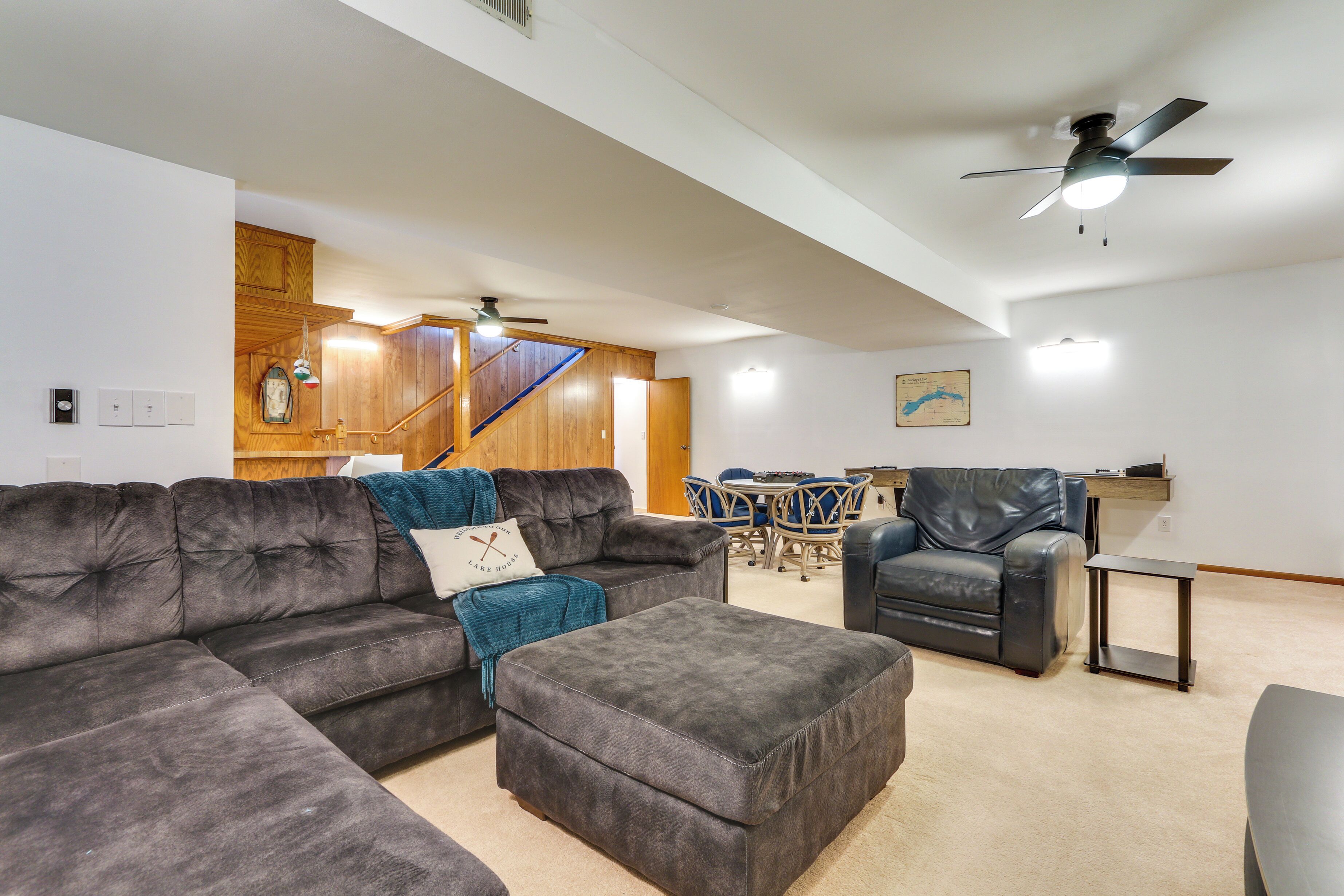 Ein großzügiger Wohnraum mit Ecksofa, Ottoman und Essbereich mit Tisch und Stühlen.