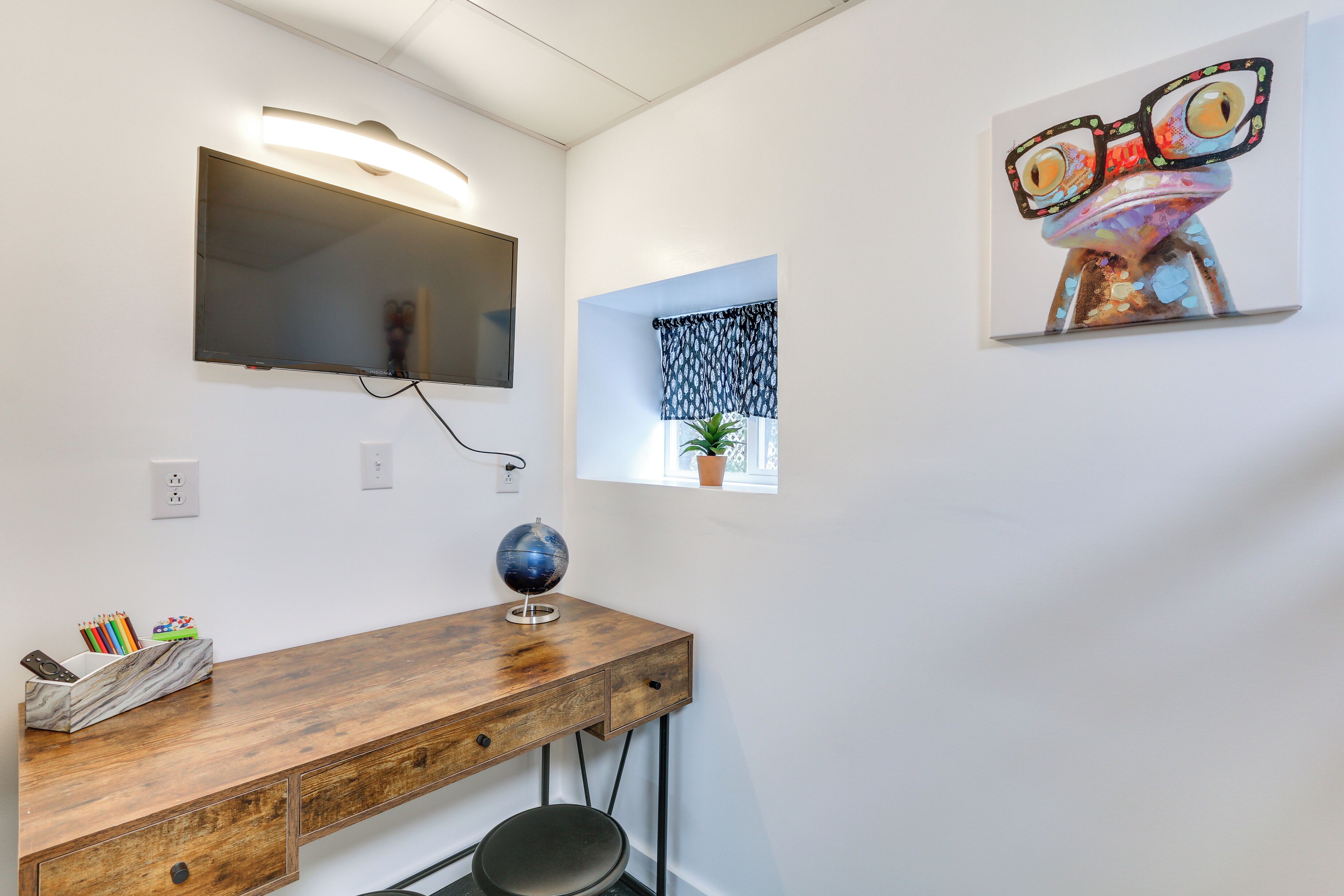 A study room with a wooden desk, a globe, and a wall-mounted TV.