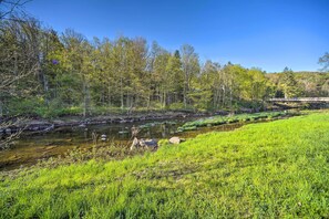 A river flowing through a forested area with a bridge in the background. - 1/2 Mi to Windham Mtn: Main Street Condo (Windham)