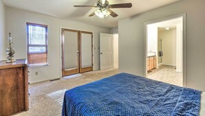 A bedroom with a bed, a ceiling fan, a dresser, and a window with blinds. - Twain Harte Home - Perfect for Large Families (Twain Harte)