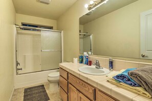 Une salle de bain avec une douche à parois de verre, un lavabo blanc, un miroir et un porte-serviettes.