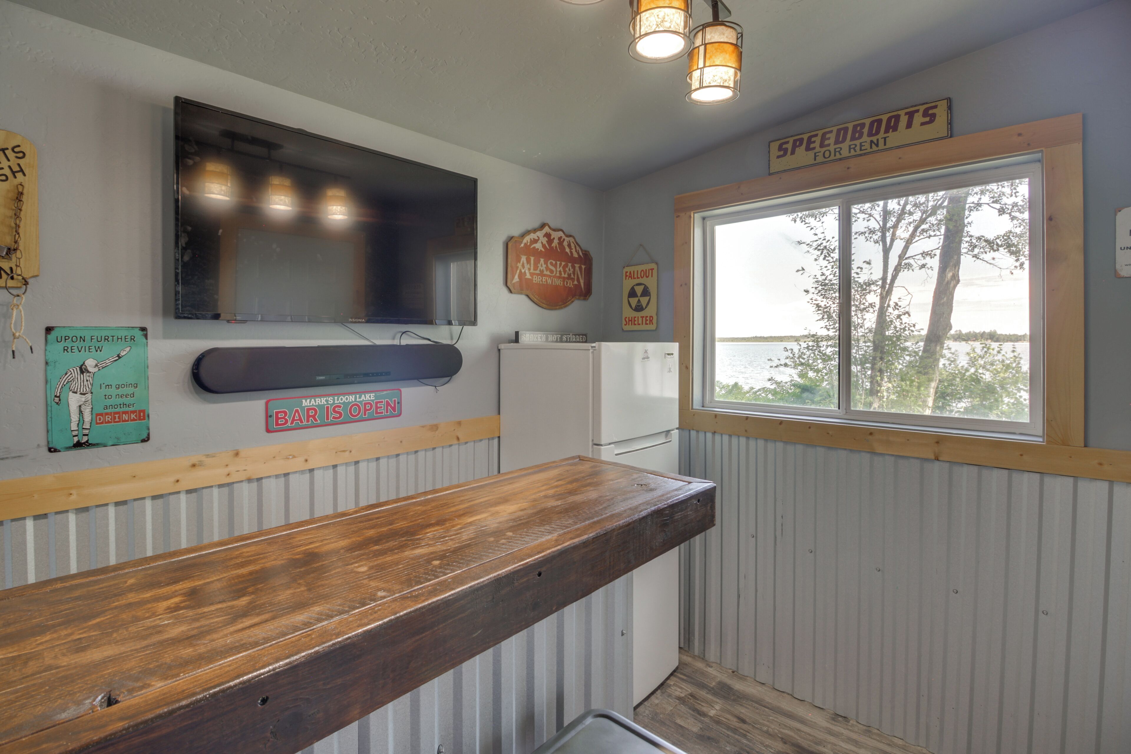 A kitchen with a wooden counter, a refrigerator, and a window with a view of trees.