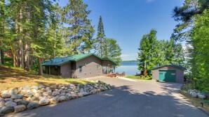 A cabin with a stone pathway leading to a dock, surrounded by trees and a lake. - Pequot Lakes Cabin w/ Dock on Loon Lake! (Pequot Lakes)