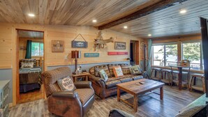 A rustic cabin interior with a wooden ceiling, a sofa set, a dining table, and a sign indicating no wake area. - Pequot Lakes Cabin w/ Dock on Loon Lake! (Pequot Lakes)
