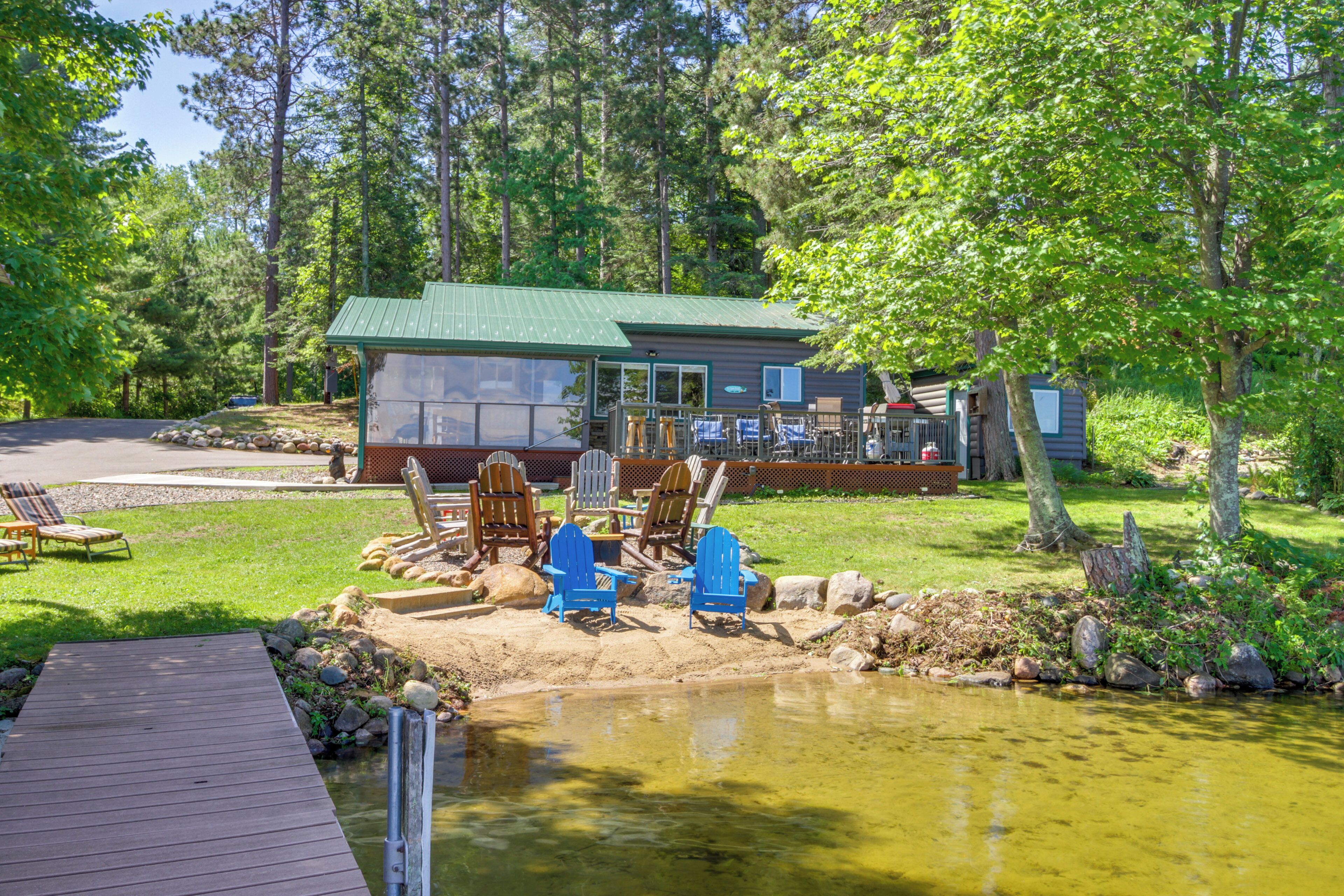 A lakeside cabin with a dock, outdoor seating, and a pond.