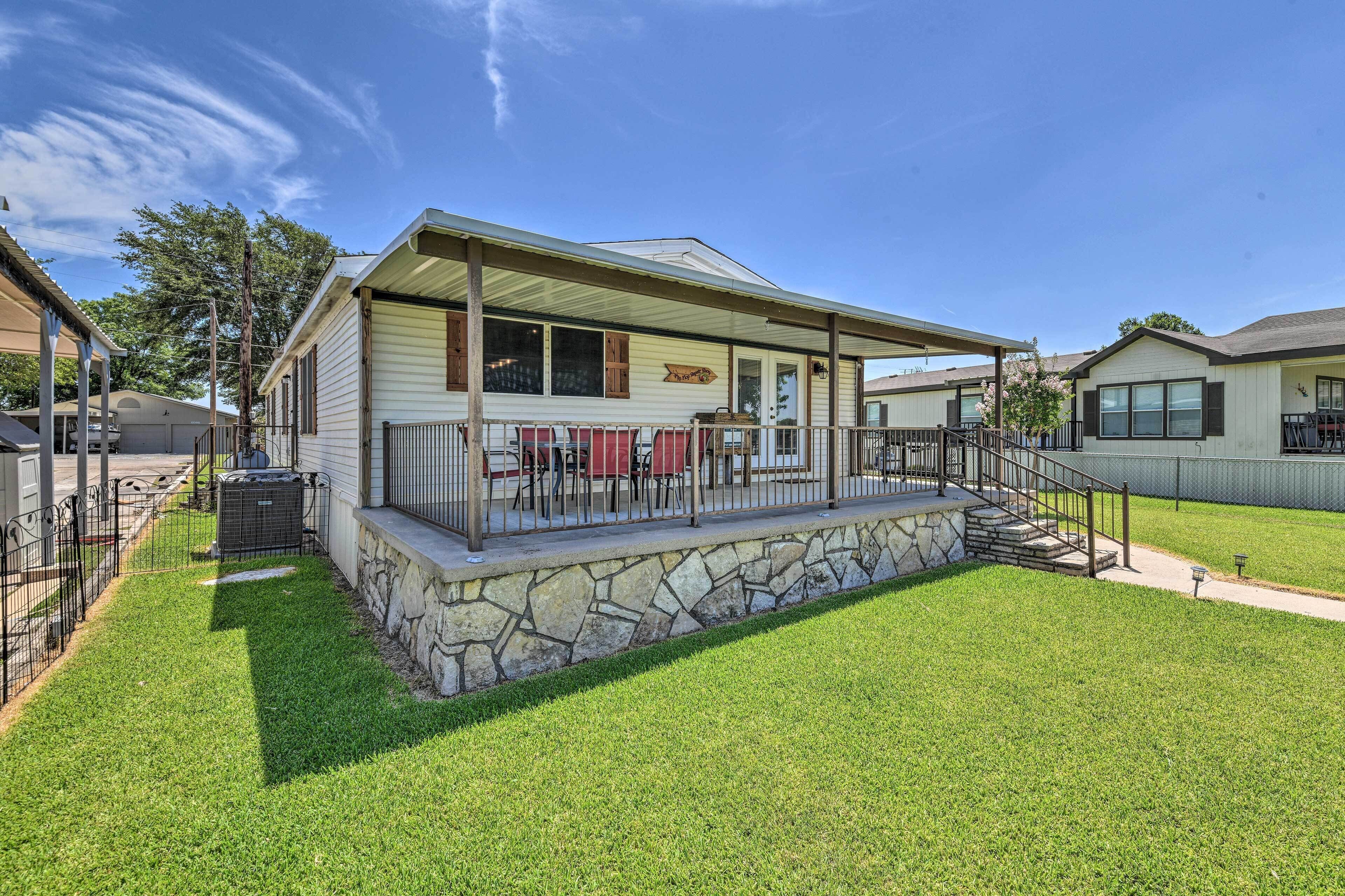 A single-story house with a covered porch, stone foundation, and a small front yard.