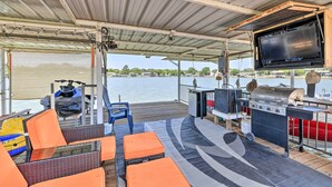Un espacio al aire libre techado con asientos, una parrilla y un televisor.