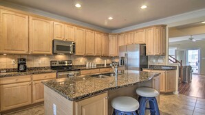 A spacious kitchen with granite countertops, stainless steel appliances, and wooden cabinetry.