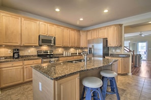 A spacious kitchen with granite countertops, stainless steel appliances, and wooden cabinetry.