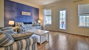 A living room with striped sofas, a white coffee table, and a ceiling fan.