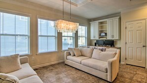 A living room with a beige sofa, a chandelier, and a cabinet with shelves.