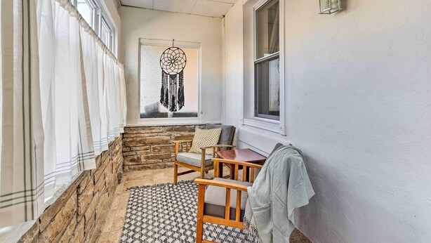 A cozy room with a stone wall, a dreamcatcher, a window with curtains, and a small table with a chair. - Philadelphia Home Rental Near Center City! (Philadelphia)
