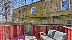 A wooden deck with a red railing, a wooden table, and a sofa with cushions. - Philadelphia Home Rental Near Center City! (Philadelphia)