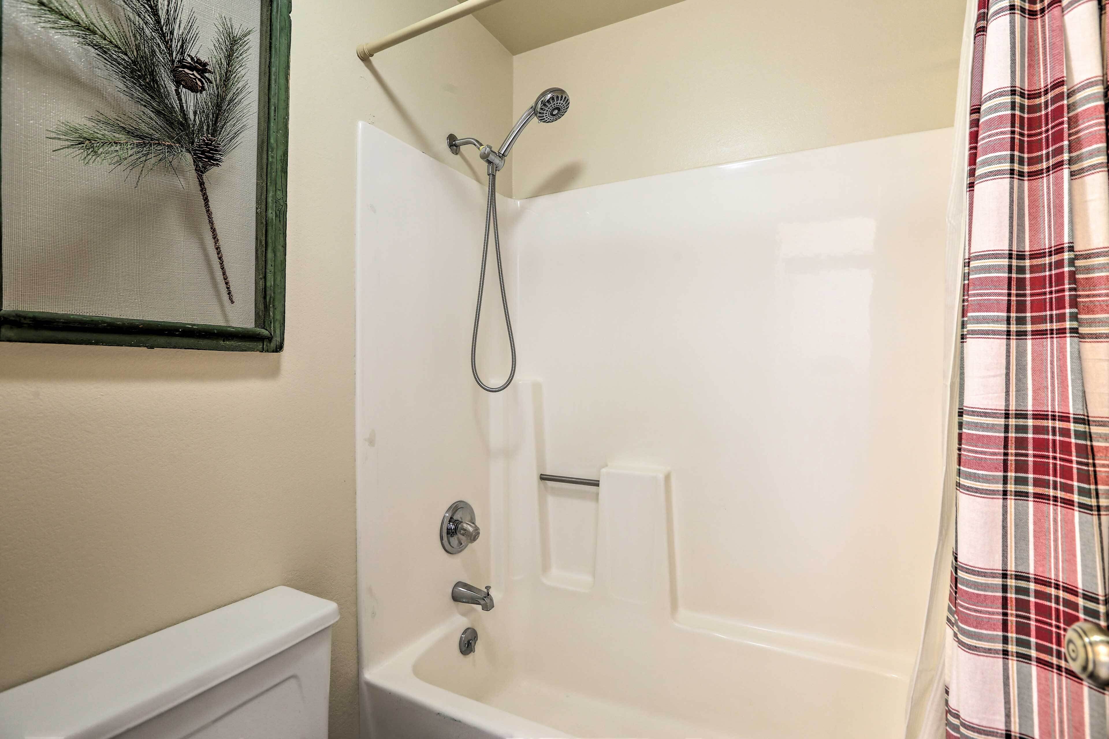 A bathroom with a white bathtub, a shower head, and a towel rack.