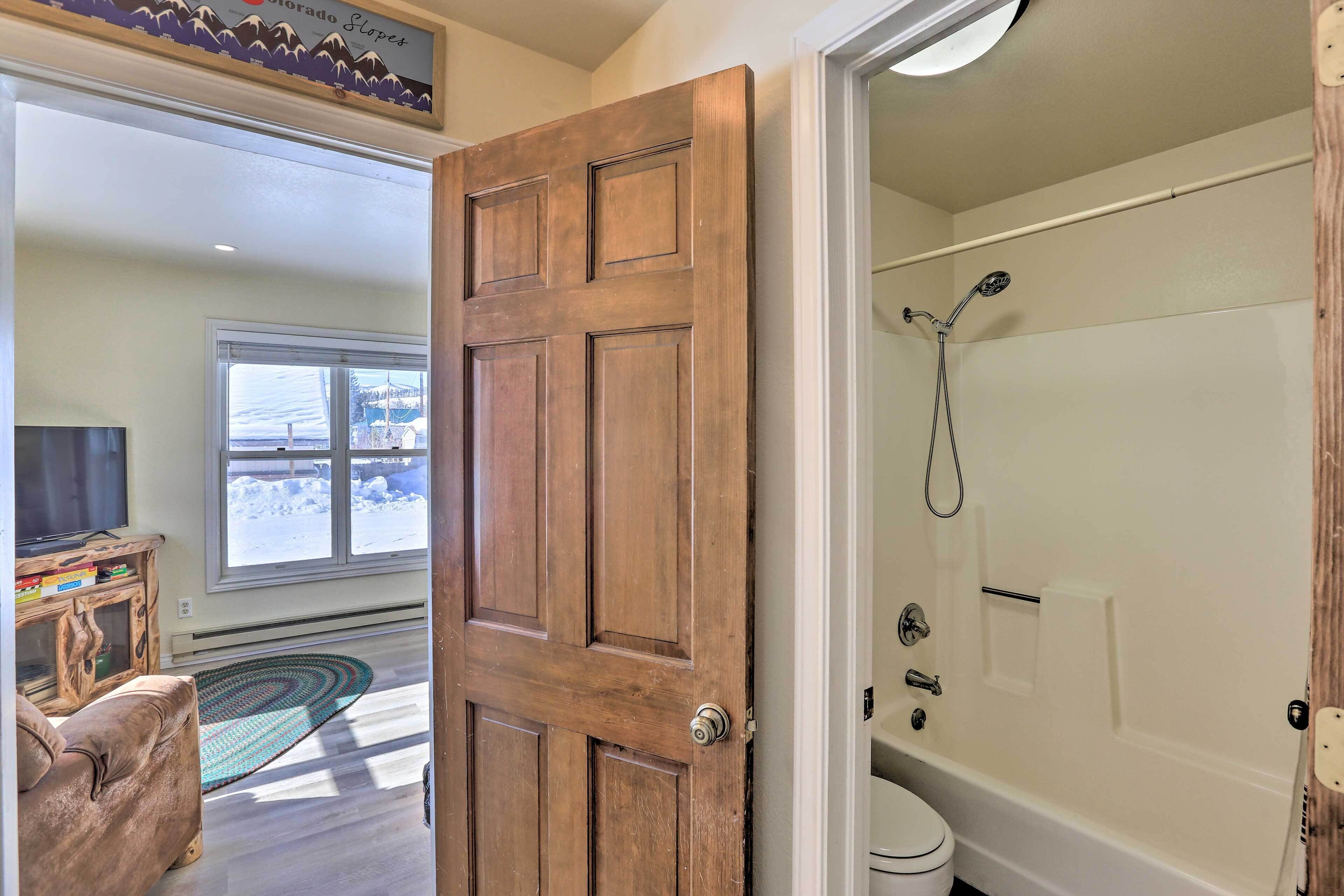 A wooden door leading to a bathroom with a bathtub and toilet.