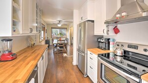 Een moderne keuken met witte kasten, roestvrijstalen apparatuur en een houten aanrecht.