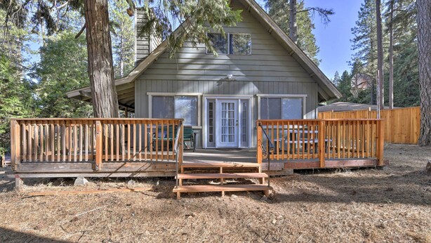 Een chalet met een houten terras, een voordeur en een raam.