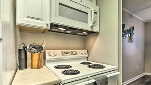 A kitchen with a white stove, a microwave above it, and a wooden utensil holder on the counter. - 1/2 Mi to Ocean City Beach! Family-friendly Haven (Ocean City)