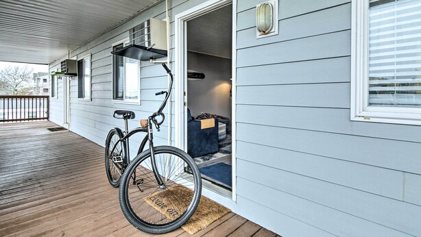 A covered porch with a bicycle, a door leading to a room with a blue chair, and a window with blinds. - 1/2 Mi to Ocean City Beach! Family-friendly Haven (Ocean City)