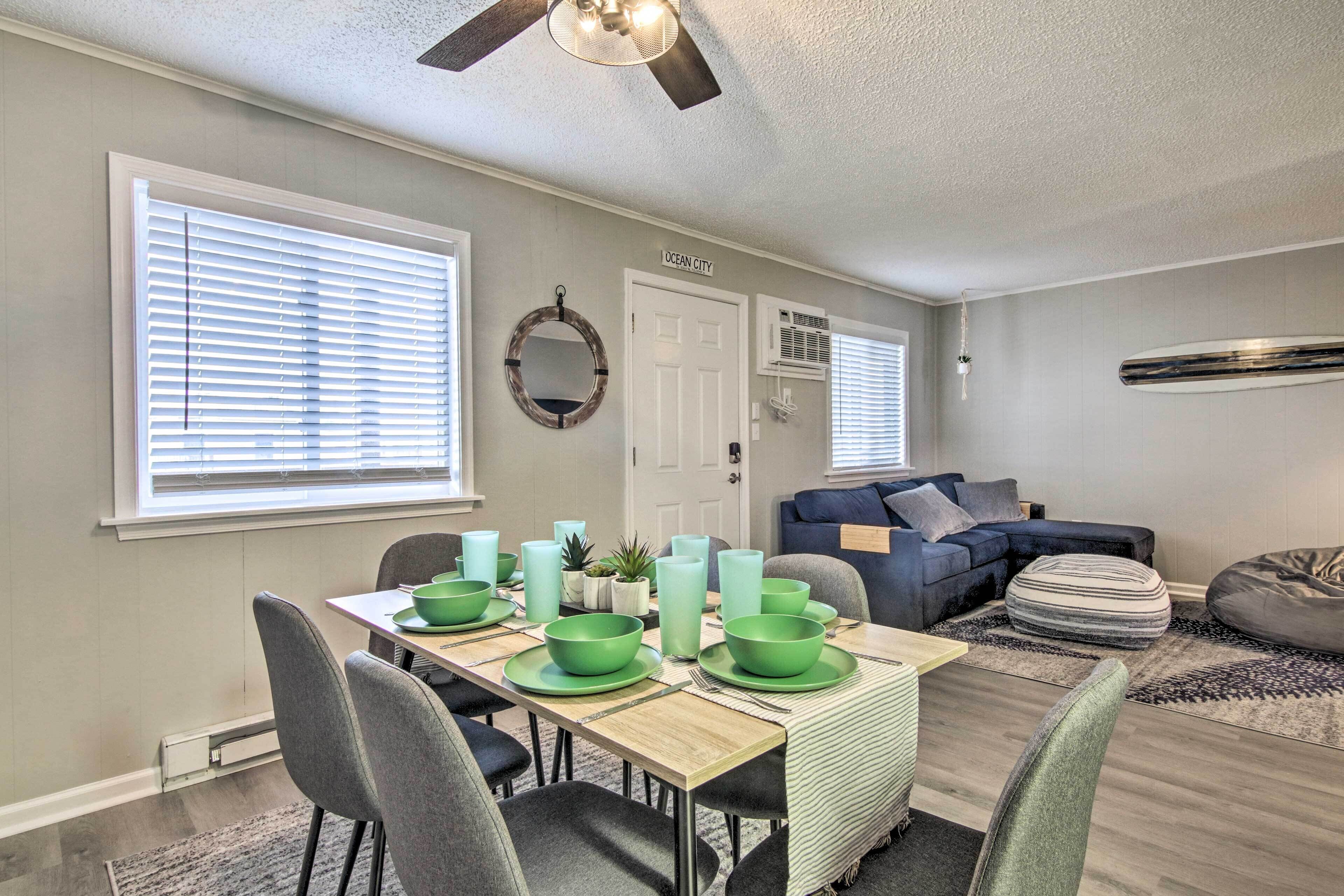 A dining area with a wooden table set for four, green plates, and bowls. There is a dark blue sofa and a bean bag chair in the background.