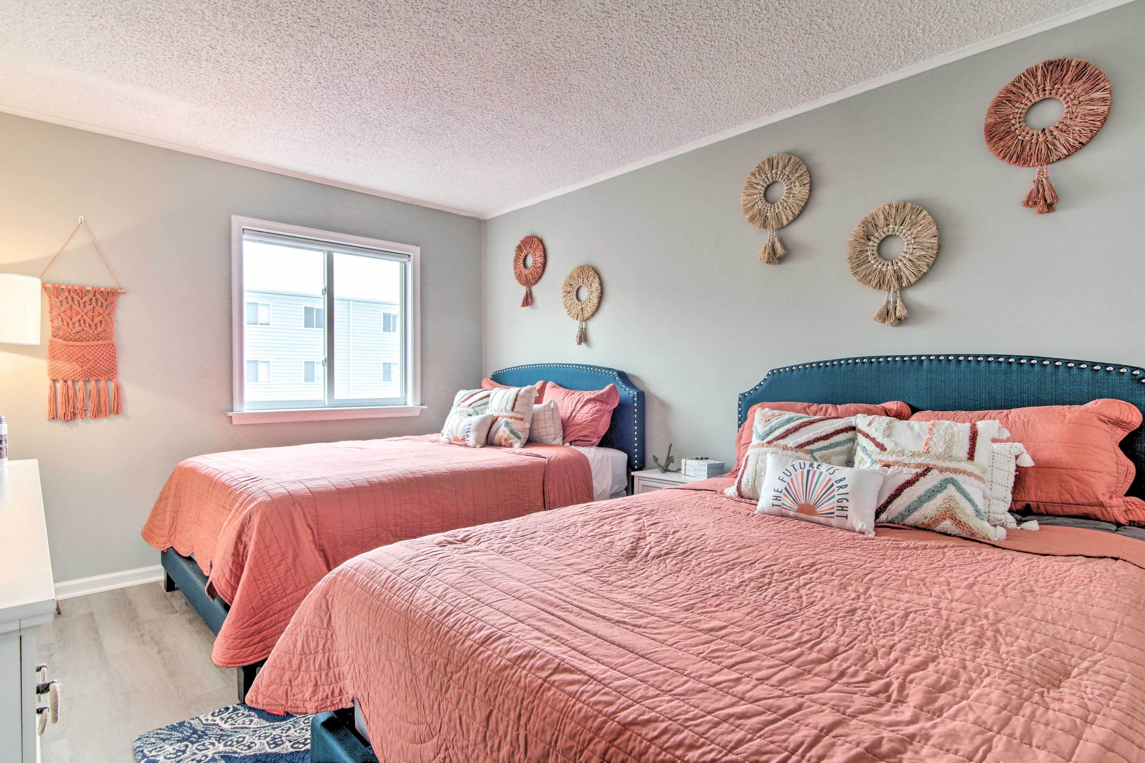 A bedroom with two beds, a window, and wall decor.