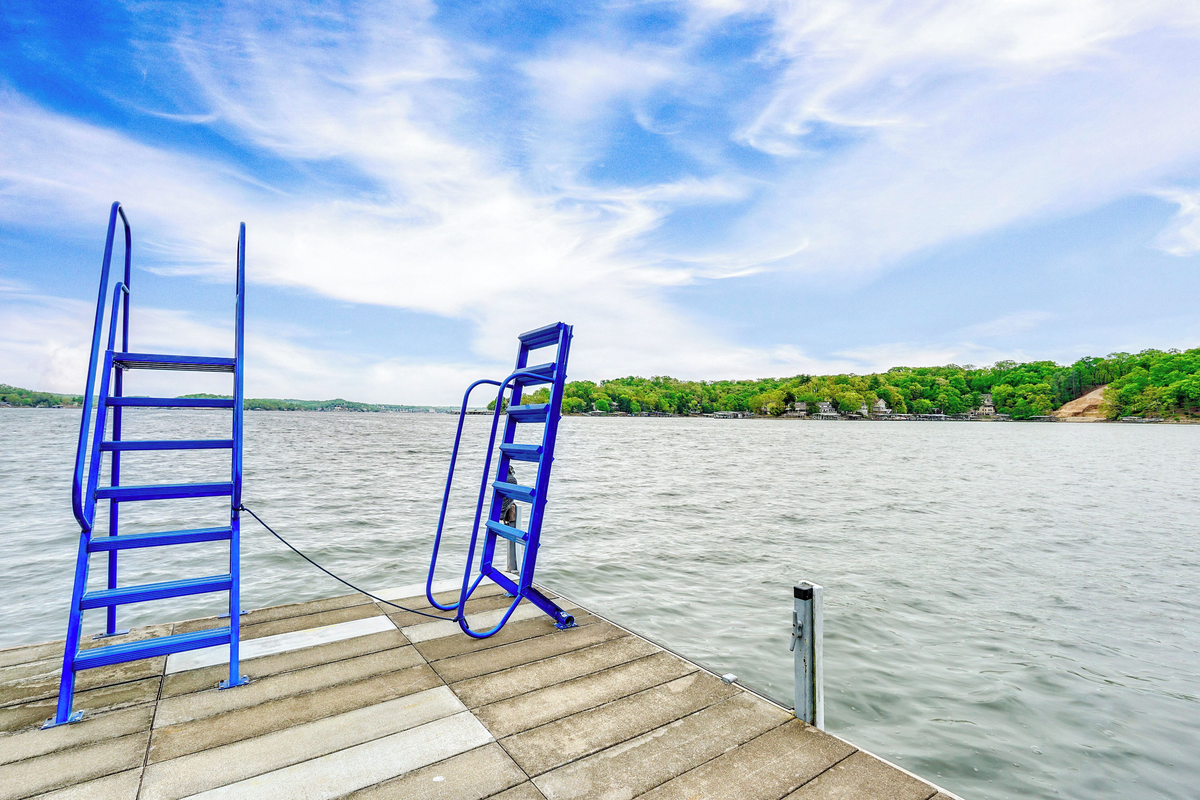 A wooden dock with two blue ladders extending over calm water.