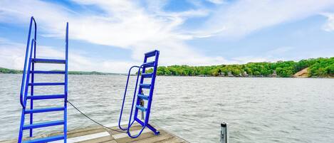A wooden dock with two blue ladders extending over calm water.