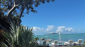 Un espace aménagé au bord de la piscine, avec des chaises longues, un quai pour bateaux et une vue sur l’océan.