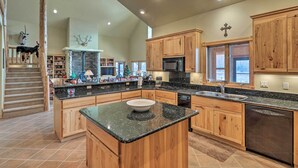 A spacious kitchen with wooden cabinets, granite countertops, and a large island. - Kalispell Riverfront Home by Glacier National Park (Kalispell)