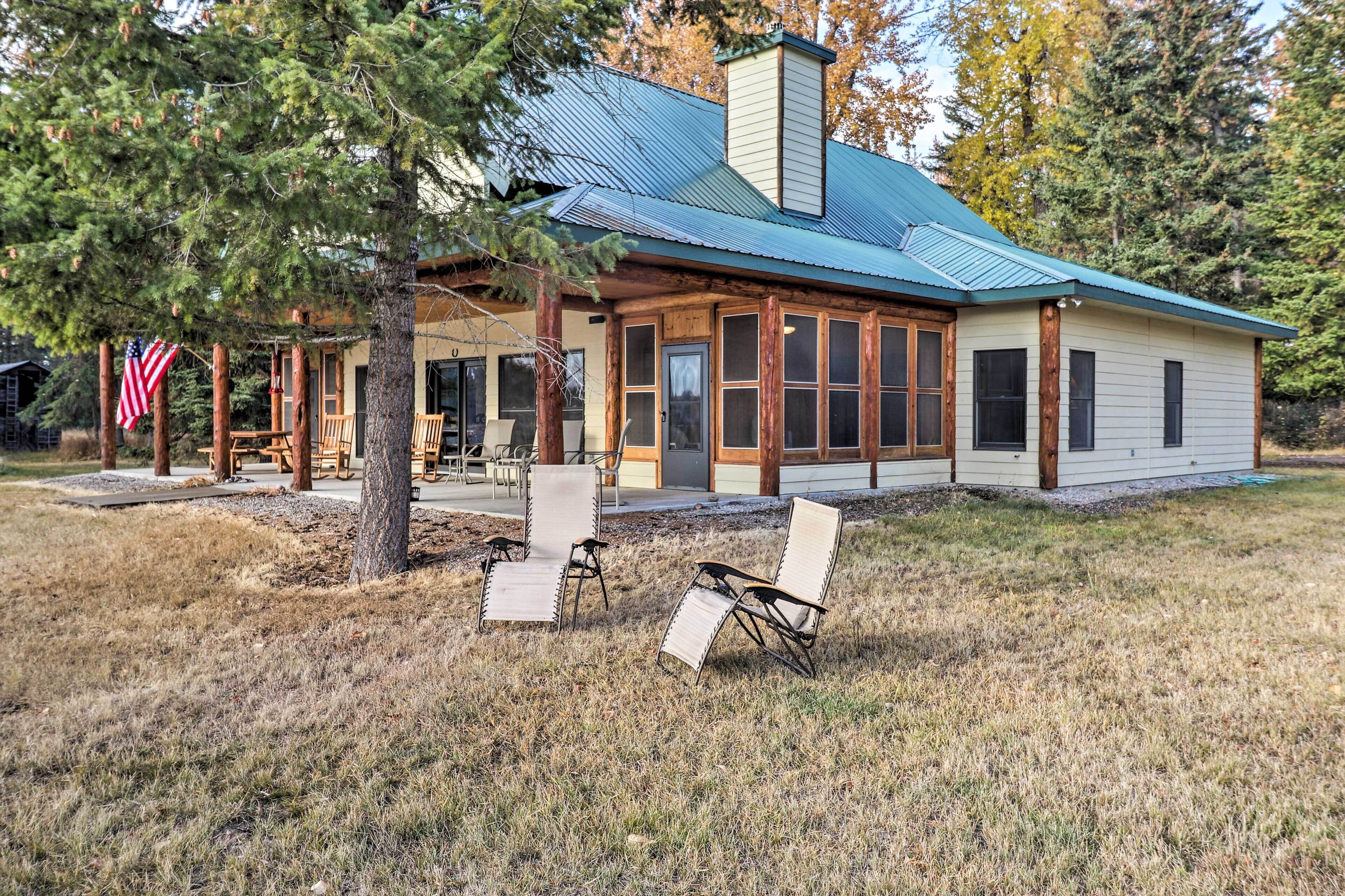 A rustic cabin with a metal roof, large windows, and a porch with outdoor seating.