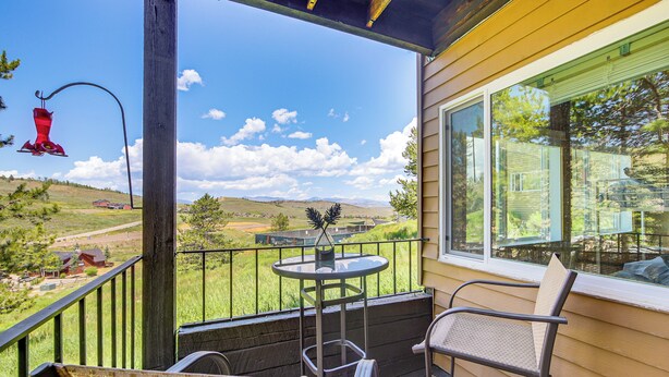 A balcony with a table and chairs, overlooking a grassy landscape and distant hills. - Ski-in/out Granby Ranch Condo w/ Balcony! (Granby)
