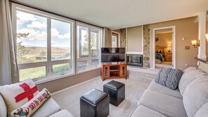 A spacious living room with large windows, a flat-screen TV, and a cozy seating area. - Ski-in/out Granby Ranch Condo w/ Balcony! (Granby)