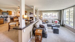 A spacious living area with a kitchen, a large window with curtains, and a cozy seating arrangement. - Ski-in/out Granby Ranch Condo w/ Balcony! (Granby)