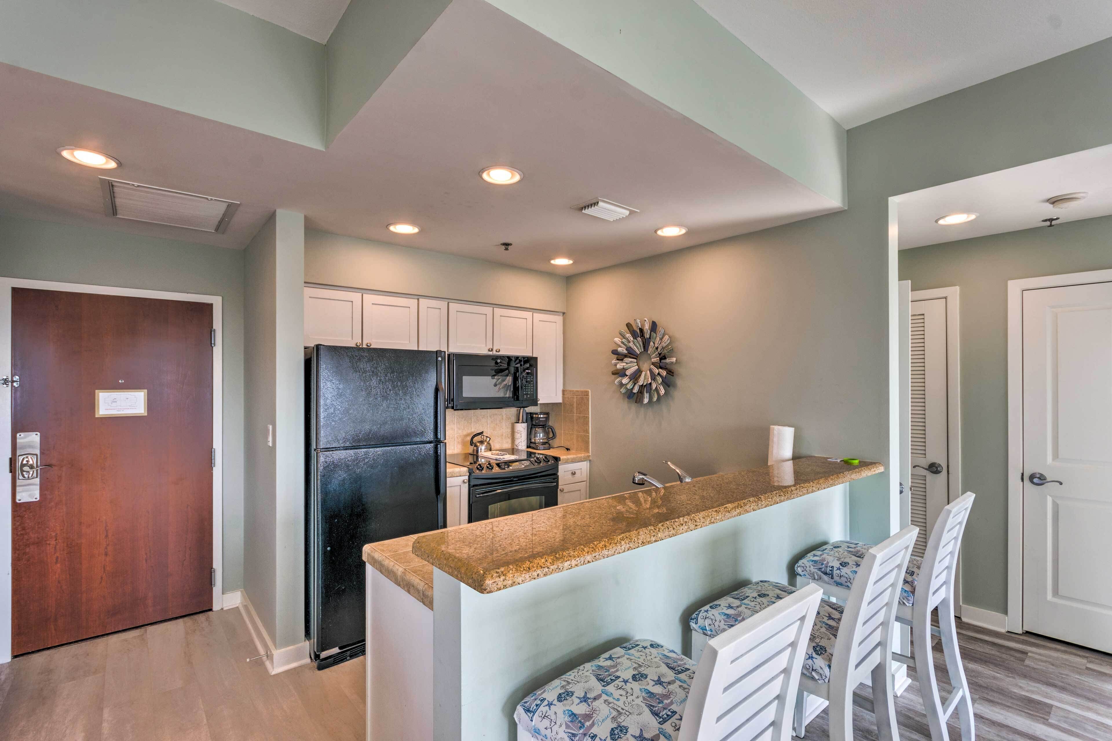 A modern kitchen with a central island, white cabinetry, and a microwave.