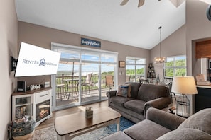 A living room with a fireplace, a sofa, a coffee table, and a TV. There is a sign that says 'happy place' and a 'welcome' sign.