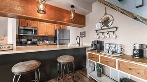 Una cucina con mobili in legno, un frigorifero in acciaio inossidabile, un forno a microonde e un angolo caffè.