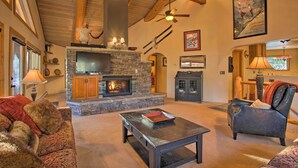 Un salón acogedor con chimenea de piedra, vigas de madera en el techo y un televisor.