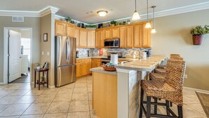 A modern kitchen with wooden cabinets, stainless steel appliances, and a central island with bar stools.