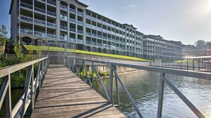 A multi-story hotel with a wooden deck leading to a river.