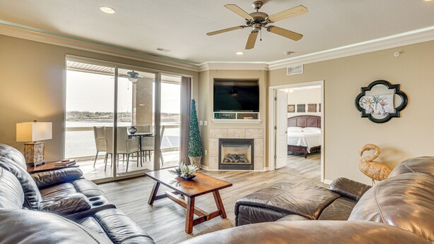 A spacious living room with a fireplace, leather sofas, a wooden coffee table, and a ceiling fan.