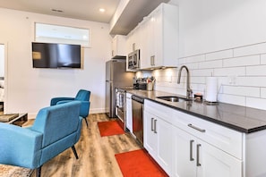 A modern kitchen with white cabinets, stainless steel appliances, and a flat-screen TV mounted above the counter. - Central Pet-friendly Apt - Minutes to Dtwn! (Philadelphia)