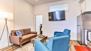 A modern living room with a sofa, armchairs, a coffee table, and a flat-screen TV.