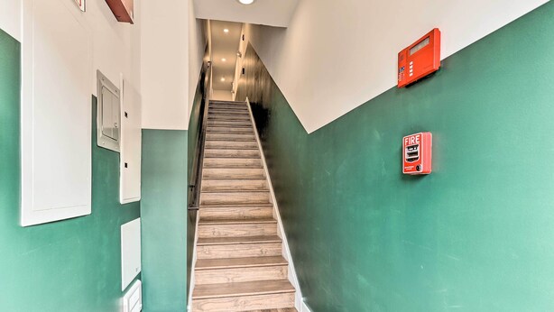 A staircase with wooden steps leading to a landing, flanked by green walls and white trim.