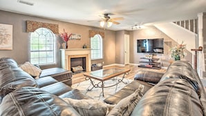 A living room with a leather sofa, a glass coffee table, a fireplace, and a television. - Gainesville Home w/ Outdoor Oasis, 16 Mi to Lake (Gainesville)