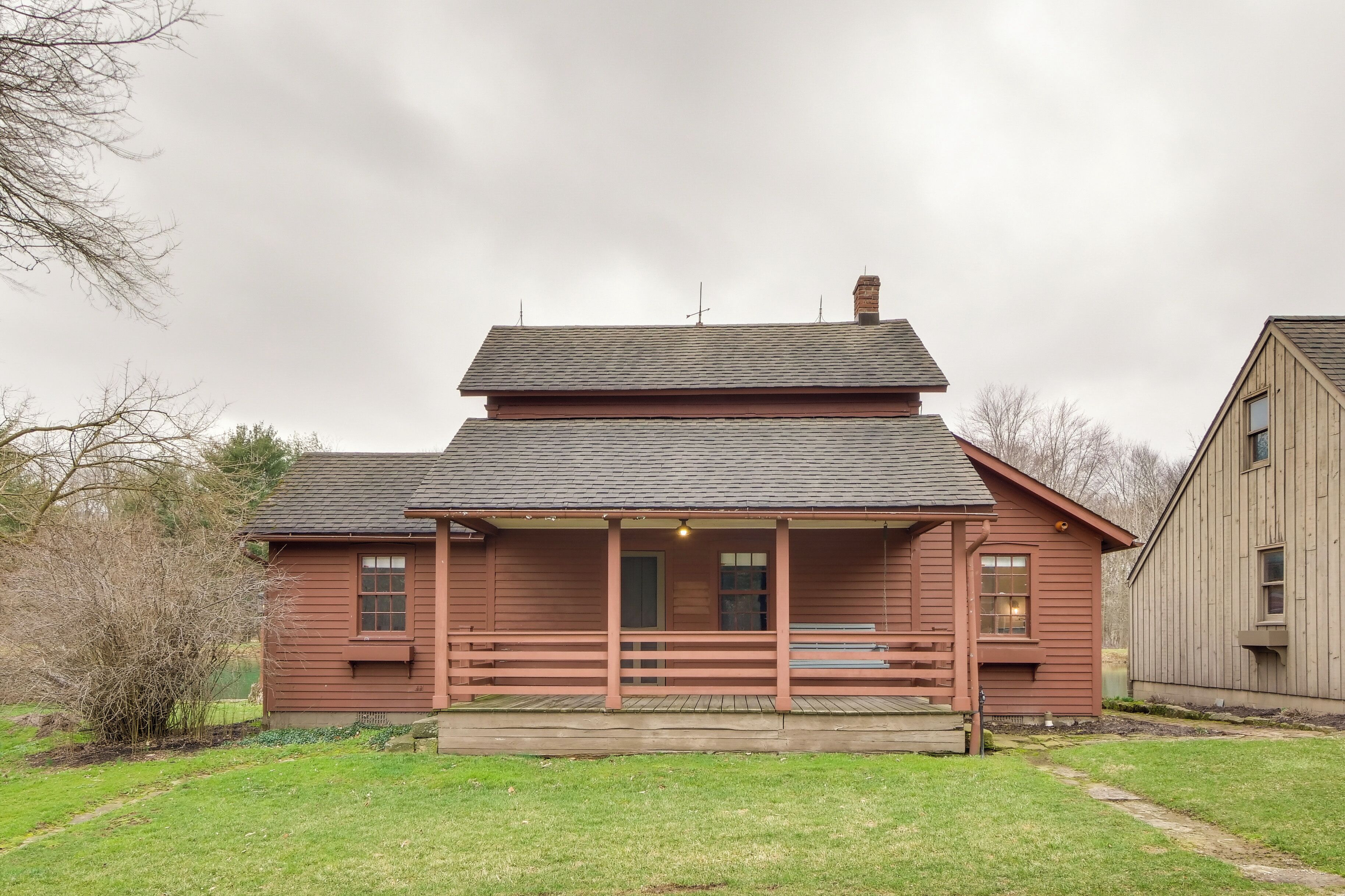 A two-story wooden building with a porch and a small garden area.