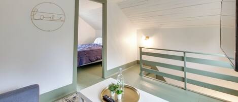 A room with a bed, a small table with a tray, a remote control, and a wall with a 'love' sign.