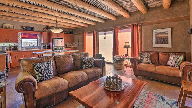 Ein rustikales Interieur mit Holzbalkendecke, Ledersofas, einem Holztisch und einer Küchenzeile.