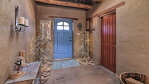 Ein rustikaler Flur mit einer blauen Tür, Holzbalken, einer Wandleuchte und einem kleinen Tisch mit einem dekorativen Gegenstand.