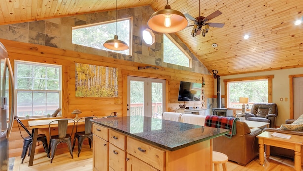 A spacious kitchen with a large island, wooden cabinets, and a dining area with chairs and a table.